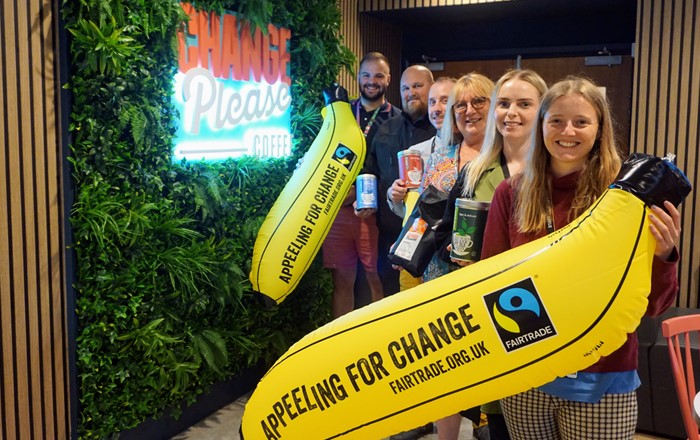 Group of six smiling people indoors holding Fairtrade products