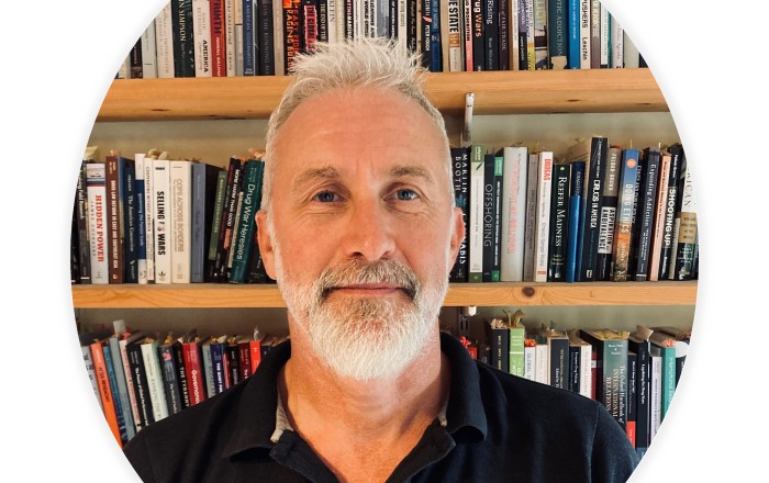 Head and shoulders photo of bearded man in front of bookcase.