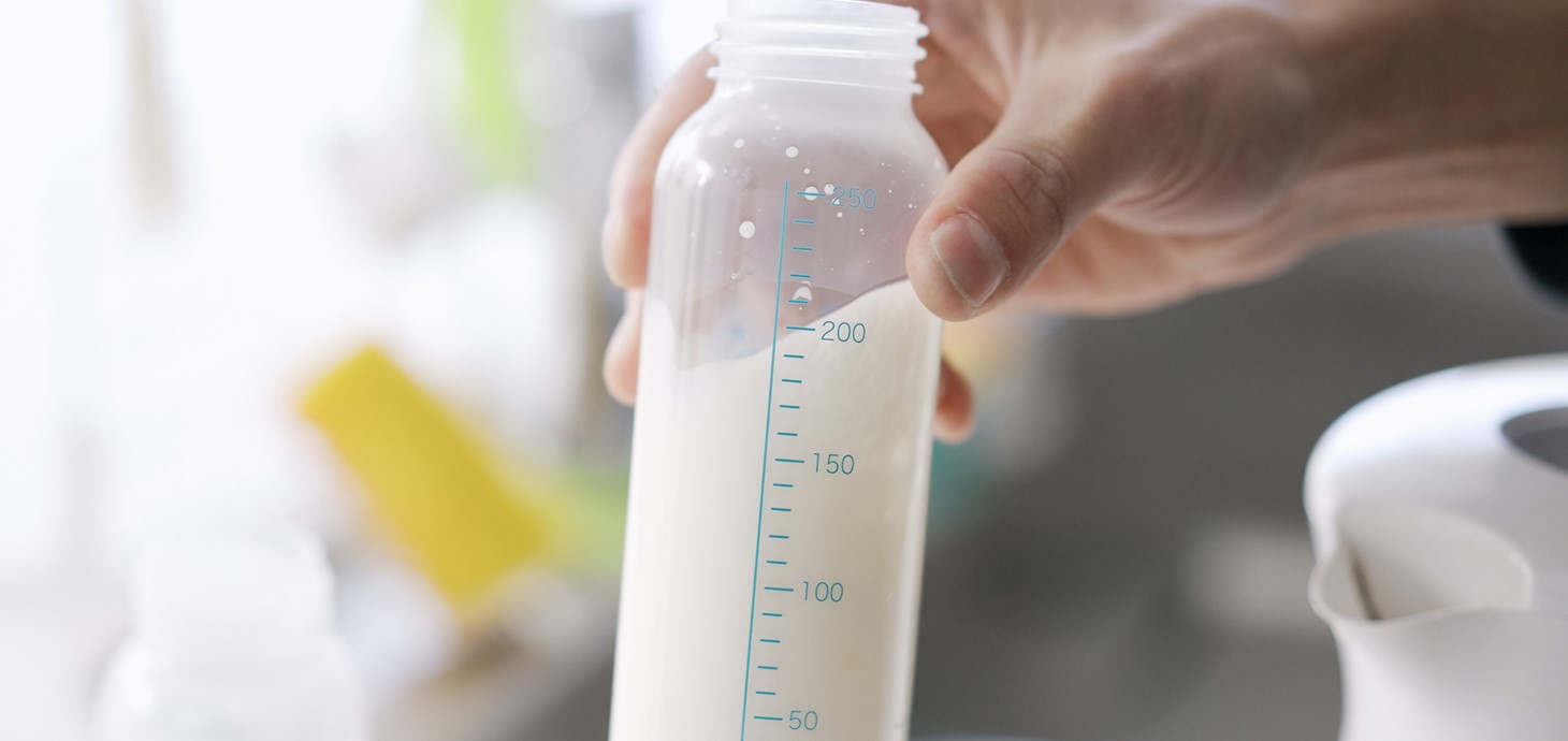 Hand holding a bottle of formula milk. 