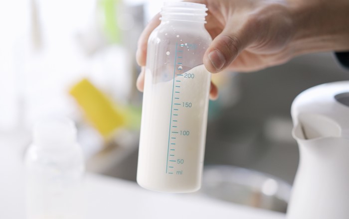 Hand holding a bottle of formula milk. 