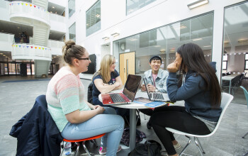 Four young people sitting round a table in a modern building