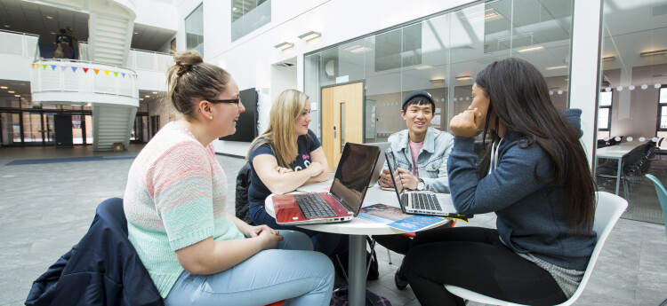 Four young people sitting round a table in a modern building