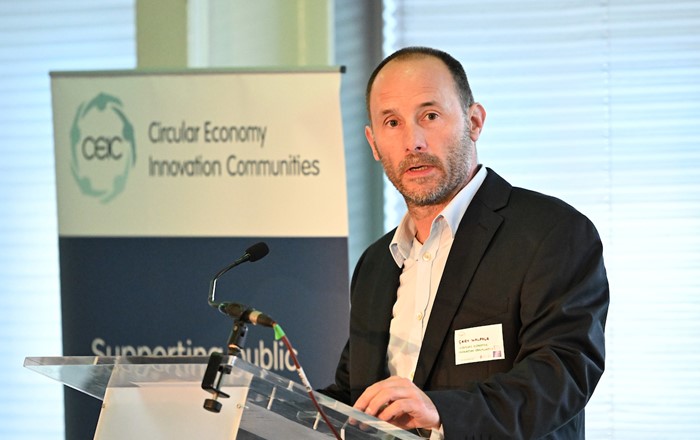 Man standing at a lectern in front of a white board.