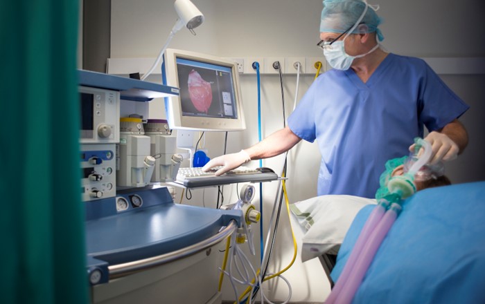 Anesthetist in a hospital room, standing by side of a patient lying down. 