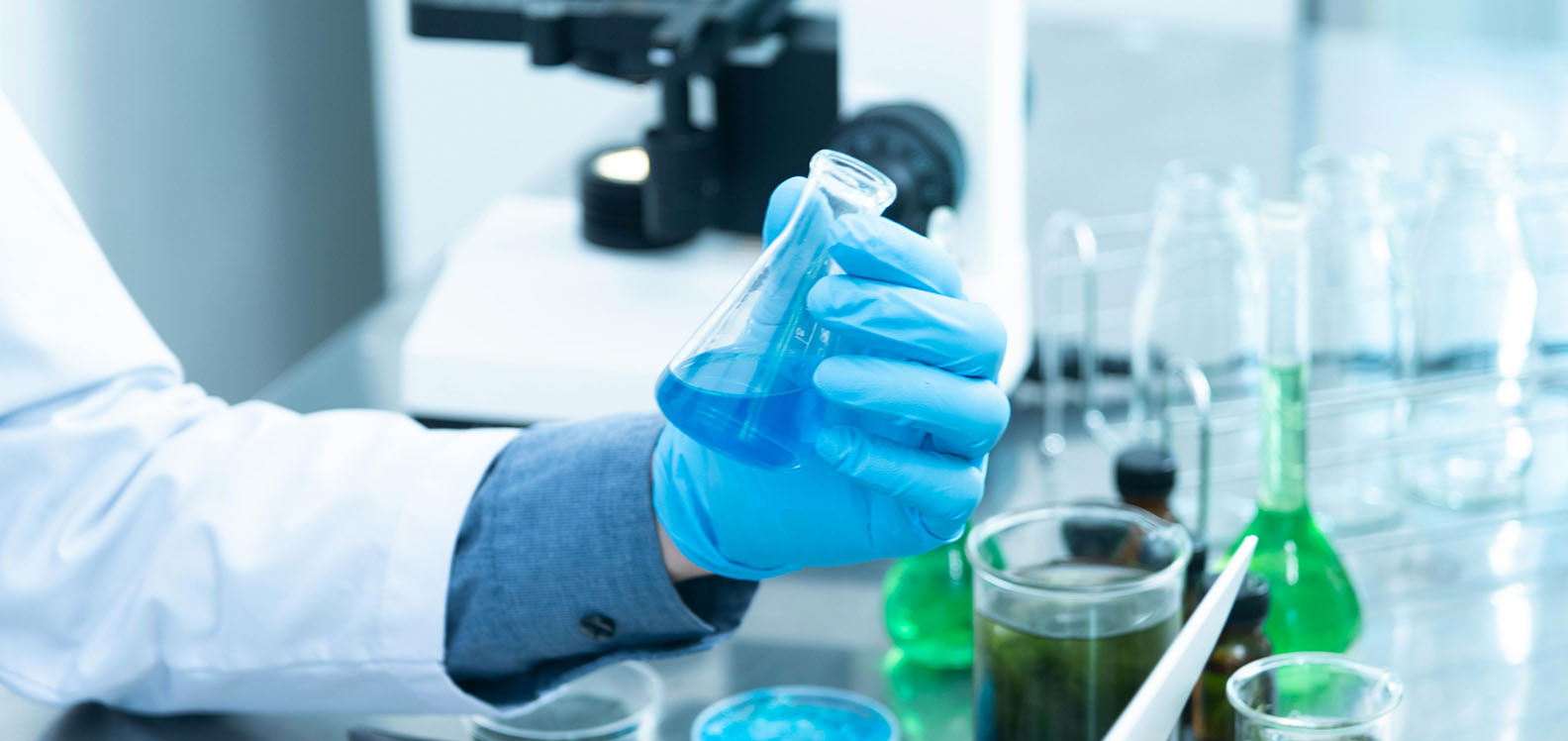 A photo of a person wearing blue gloves holding a beaker.