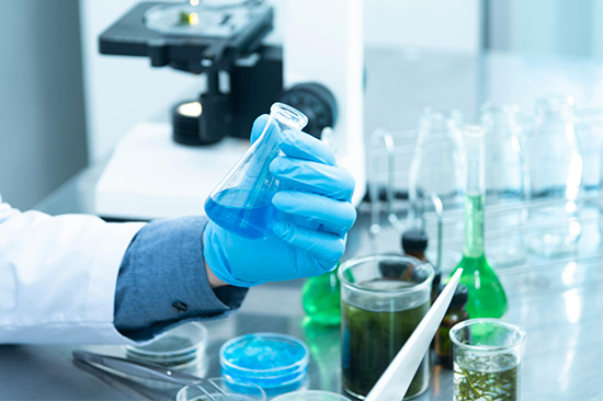 A photo of a person wearing blue gloves holding a beaker.