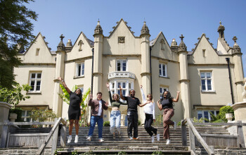 A group of students jump for joy outside Singleton Abbey 