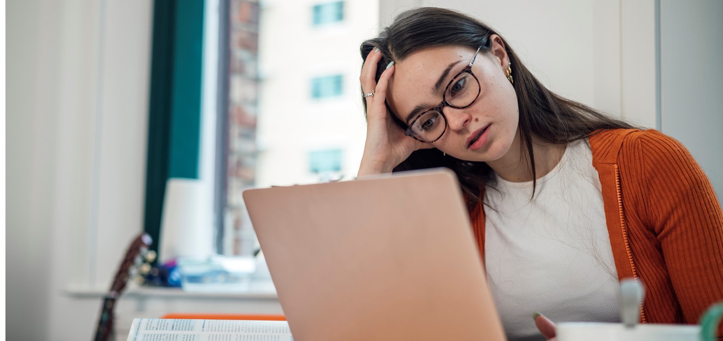 A student with her head in her hand looking at a laptop