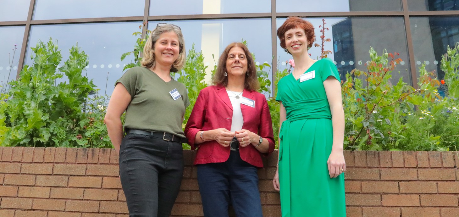 Three smiling women standing in front of a building