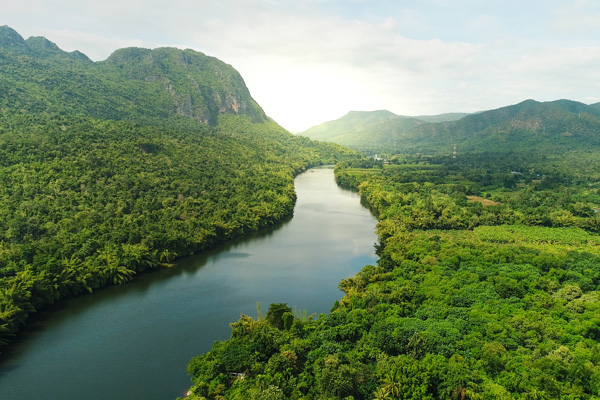 Beautiful natural scenery of river in southeast Asia tropical green forest with mountains in background