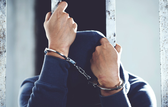 Person in handcuffs behind bars