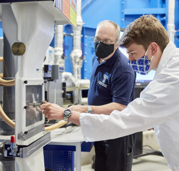 image of mechanical engineering student operating machinery with a technician 