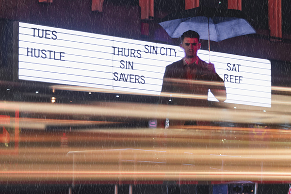 A man stands in front of a bar with an umbrella