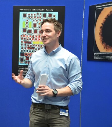 Man standing in front of blue board