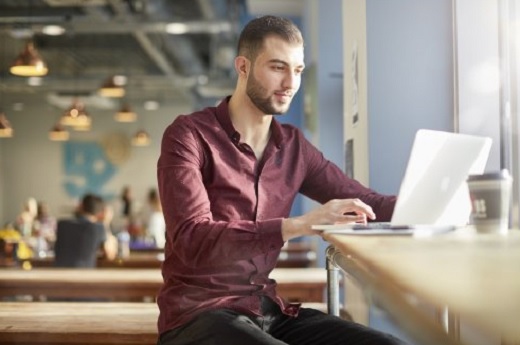 A man in a red shirt sitting at a computer 