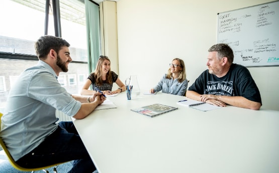 postgraduate researchers talking and laughing, sitting at a table