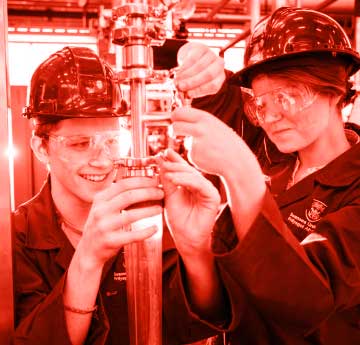 A male and female student engineering student working on a piece of equipment