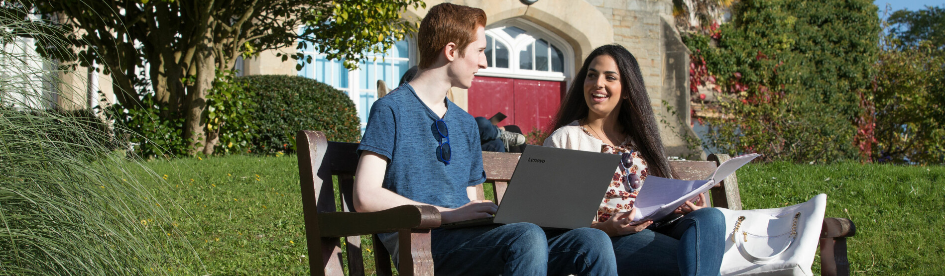 students with laptops on bench