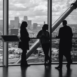 business professionals standing in the window of a high rise. 