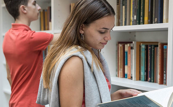 Student looking thoughtfully at a book in the library