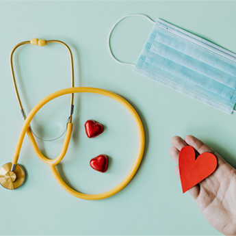 A stethoscope, face covering and a paper heart 