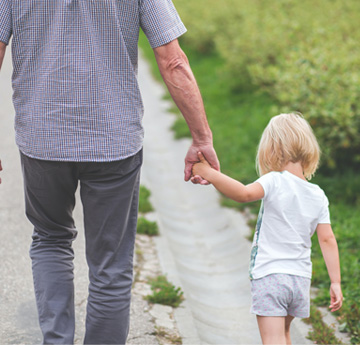 An elderly man and his granddaughter walk hand in hand 