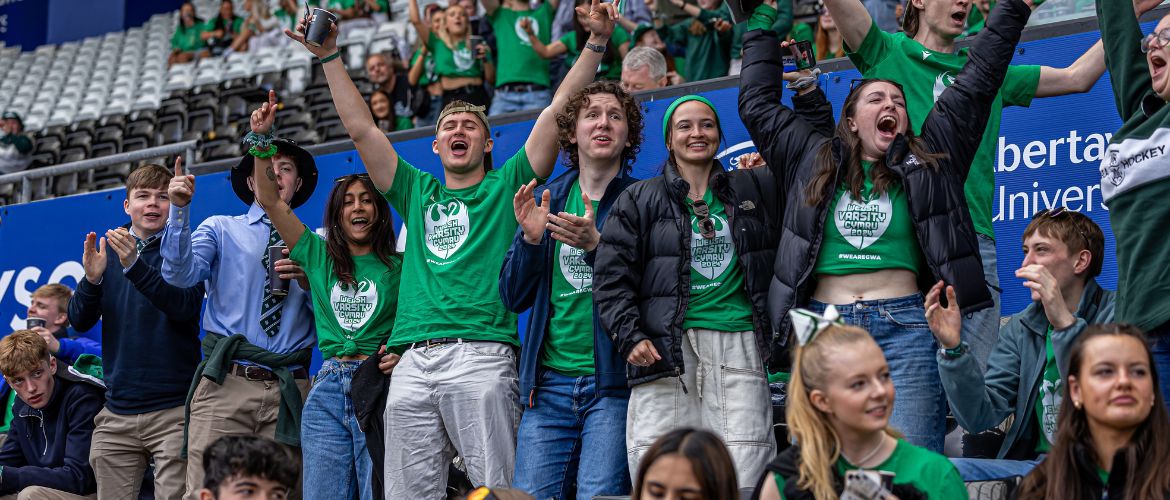 Students at the Liberty Stadium waving Sport Swansea flags during Varsity. 