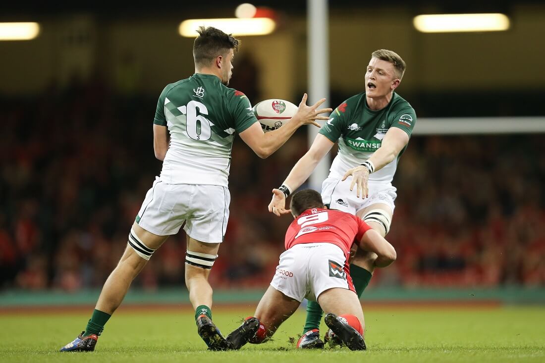 Man throwing the ball to his teammate whilst being tackled