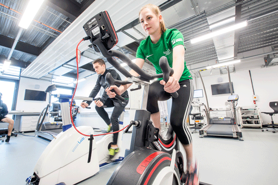 Female sport scientist student on stationary bike