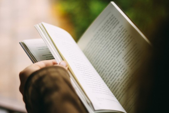 Artistic shot over the shoulder of a person flipping through pages of a book