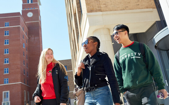 three students walking outside university buildings