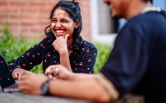 Student sitting down outdoors socialising with peers