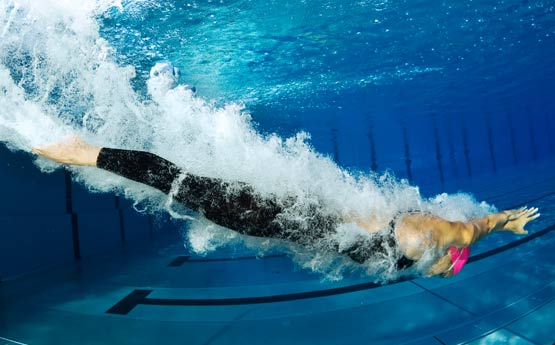 Swimmer diving into a brilliant blue pool