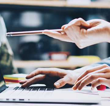 Two people hands pointing at a laptop