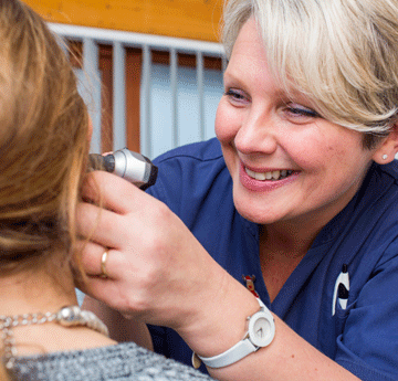 The nurse looking in a students ear