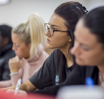 Four people making notes in a lecture