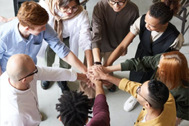 A group of people stood in a circle with their hands on top of each other