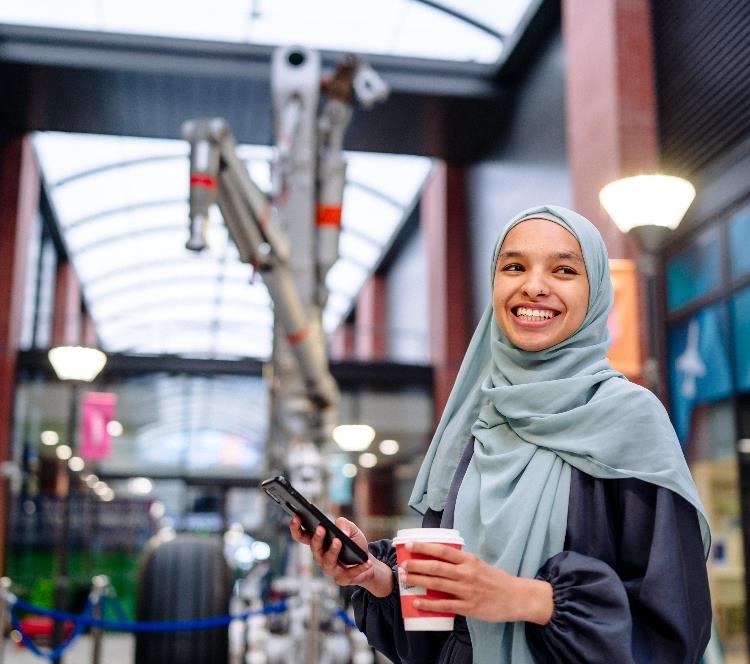 Female student with mobile phone and coffee in Engineering