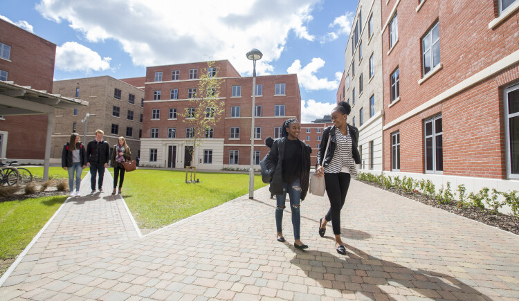 Two people walking through accommodation block.