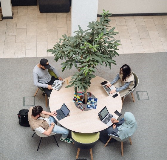 Students in discussion and working on laptops in The College