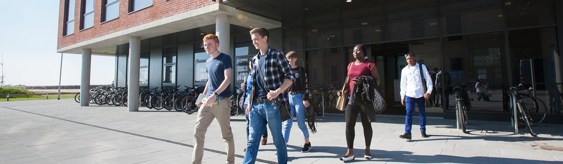 Student walking outside the School of Management on the Bay Campus of Swansea University.