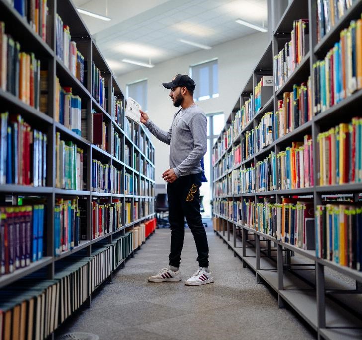 Student holding booking in library.