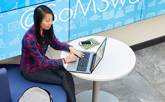 Students talking at table with laptops open.