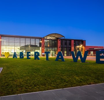 Engineering building at night with a sign saying Abertawe in front of it