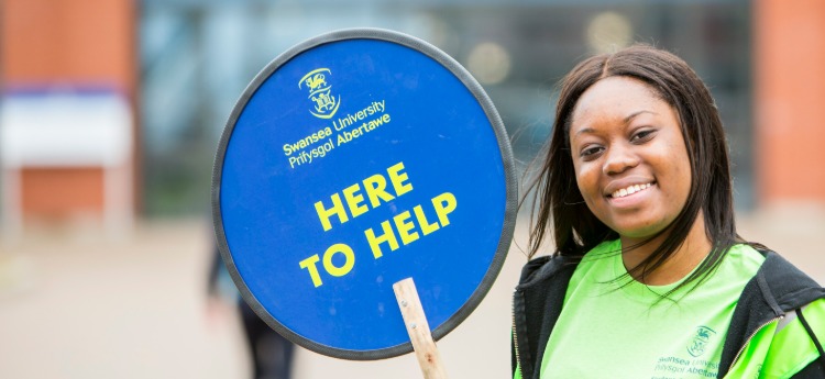 Student ambassador with a 'Here to help' placard