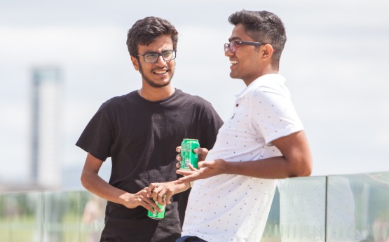 Two international students casually conversing with a drink in the sun