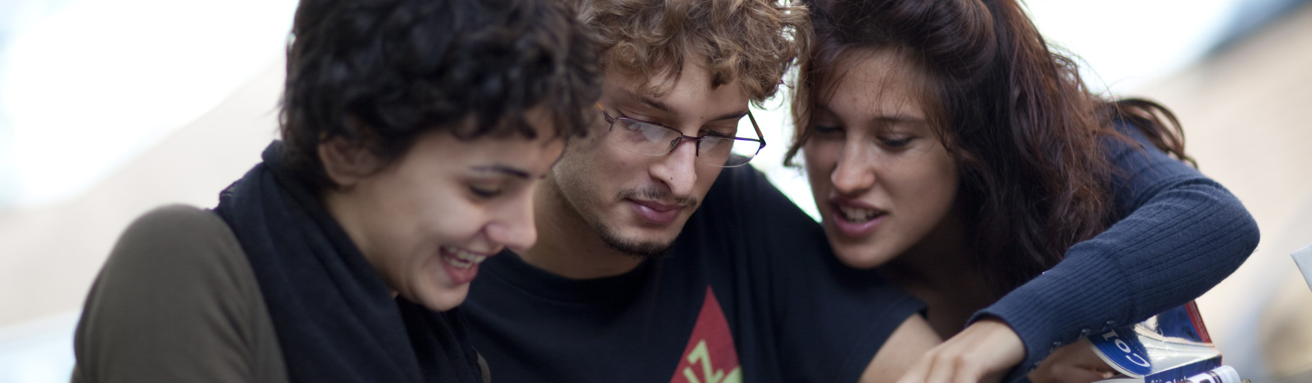 Three students collaborating and looking down at their work 